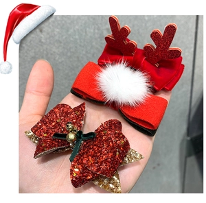Close-up of Christmas hair clips with plush deer antlers, glitter bows and gold bells