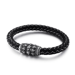 Braided black leather bracelet with silver skull charm and buckle on white background