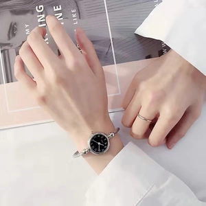 Close-up of elegant silver bangle watch with black dial and twisted metal rope band