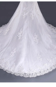 Dettagli del ricamo in pizzo e paillettes sullo strascico dell'abito da sposa bianco