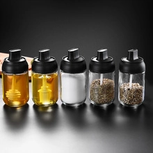 Five-piece set of clear glass seasoning jars with black lids and integrated spoons