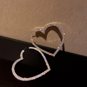Close-up of heart-shaped silver earrings with sparkling rhinestones and shadow effect