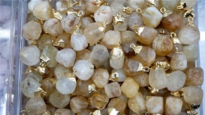 Macro detail of natural faceted citrine raw stone pendants with gold plated caps