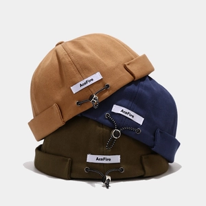 Drei Docker-Mützen in Camel, Marineblau und Olivgrün mit verstellbarem Kordelzug und Label