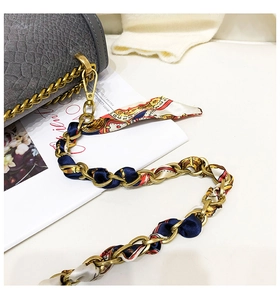 Dettaglio del foulard di seta stampato intrecciato con tracolla a catena in metallo dorato