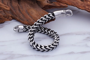 Close-up of 316L stainless steel woven chain bracelet on marble surface with wood accent