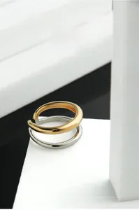 Gros plan sur la bague ouverte bicolore à double couche sur un support géométrique minimaliste