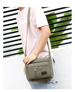 Detailed view of army green canvas crossbody bag featuring multi-pocket design and adjustable strap