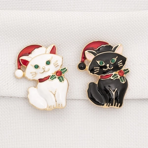 Close-up of black and white Christmas cat brooches with red and green rhinestones