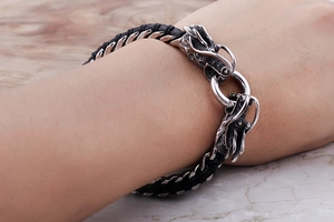 Close-up of dragon head stainless steel and black braided leather bracelet on wrist