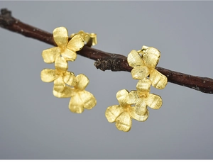 Macro shot of matte gold triple flower earrings featuring a brushed metallic texture