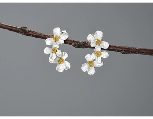 Detailed macro shot of matte S925 sterling silver daisy earrings on a dry twig branch