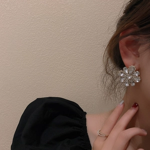 Detailed close-up of sparkling crystal flower earrings worn by a model in soft light