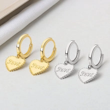 Detailed view of gold and silver heart earrings with beaded edges and LOVE engraving