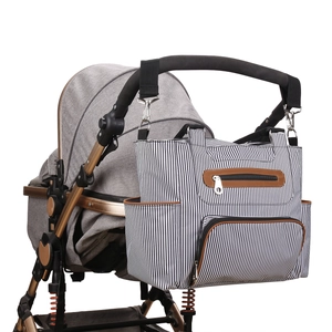 Detail of black and white striped diaper bag hanging on a stroller with storage pockets