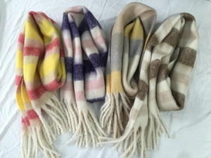 Detail shot of four striped winter scarves with fringe tassels on white fabric