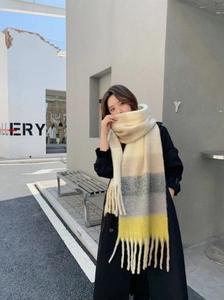 Detail of soft winter scarf with beige, grey and yellow gradient stripes and fringe