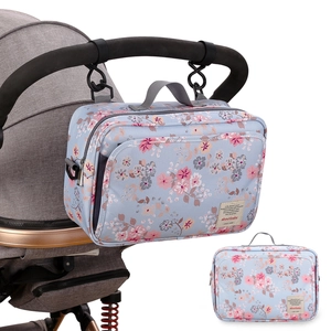 Detail der hellblauen Kinderwagentasche mit Blumenmuster hängend am Kinderwagengriff