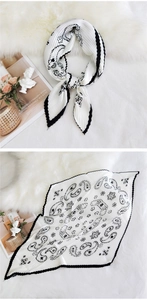 Detail of pleated silk scarf featuring black paisley patterns on an ivory white background