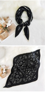 Close-up of pleated black silk scarf with white paisley print and wavy scalloped edges