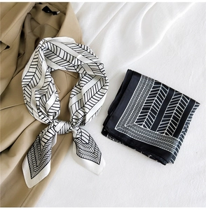 Detailed view of black and white herringbone silk scarf on a stylish khaki trench coat