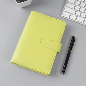 Detail of neon green leather notebook with magnetic buckle on a grey workspace desk