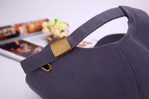 Detail of adjustable metal buckle on dark grey-purple baseball cap with fine stitching