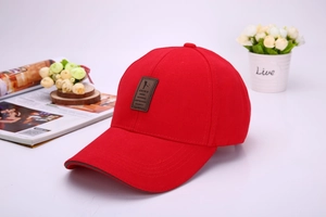 Close-up of a red baseball cap featuring a premium leather patch and golfer silhouette