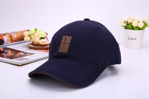 Detail of navy blue cotton baseball cap featuring brown leather patch and stylish brim piping