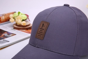 Close-up of deep gray-purple cotton baseball cap with premium brown leather logo patch