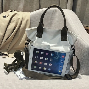 Detail view of large cream canvas tote bag with green handles next to an iPad for size reference