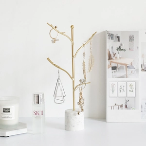 Golden branch jewelry stand with marble base for organizing earrings and necklaces