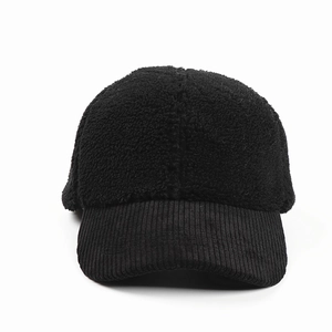 Texture detail of black sherpa fleece and corduroy patchwork on a winter baseball cap