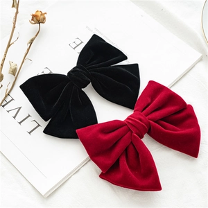 Detail of red and black velvet bow hair clips placed on a magazine page
