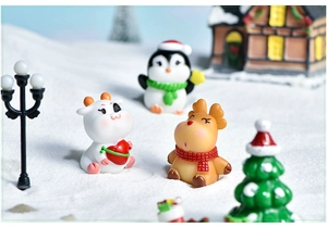 Close-up of resin Christmas miniatures featuring a cute penguin, cow and reindeer