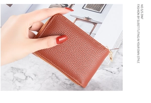 Close-up of brown litchi pattern leather card holder with golden zipper detail