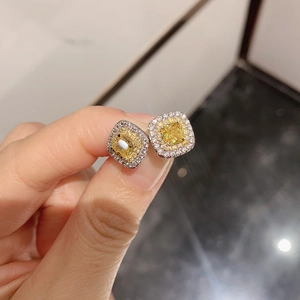 Macro detail of square halo stud earrings with yellow gemstone and clear zircon accents