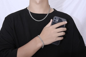Close-up of a silver titanium steel chain necklace and bracelet set on a male model