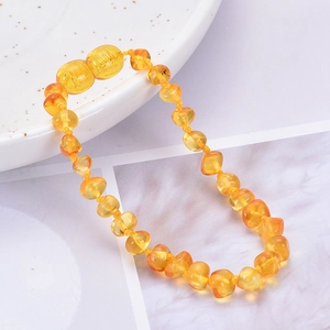 Natural irregular amber baby bracelet with warm yellow translucent beads on a white tray