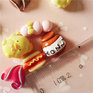 Macro shot of assorted resin charms like honey pot and chick with a measuring ruler