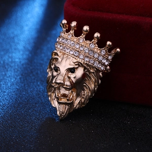 Close-up of golden lion head brooch with crown and rhinestones on red velvet box