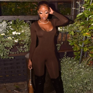 Detail of slim fit dark brown long sleeve jumpsuit with deep V-neck in outdoor setting
