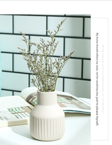 Close-up of cream ceramic vase featuring vertical ribbed texture with dried lavender flowers