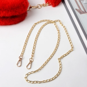 Detail of red faux fur plush accessory with elegant gold chain and carabiner clips