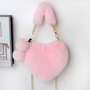 Detailed view of pink heart-shaped plush handbag with fluffy charms and gold chain