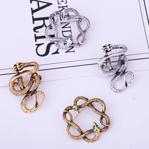 Detailed macro view of four vintage snake brooches in antique silver and gold finishes