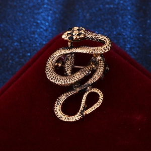 Detailed close-up of vintage bronze snake brooch with black gemstone eyes and scaled texture