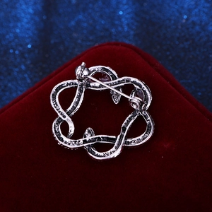 Vintage silver double snake brooch with antique metal texture on red velvet background