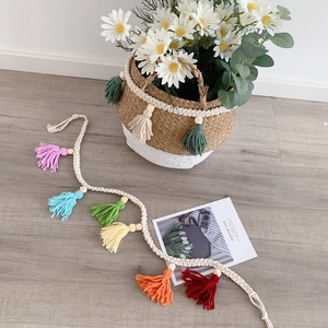 Detail of colorful cotton tassels with wooden beads on a woven boho wall hanging