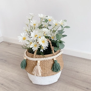 Detail of woven straw basket with colorful tassels, wooden beads and white daisies